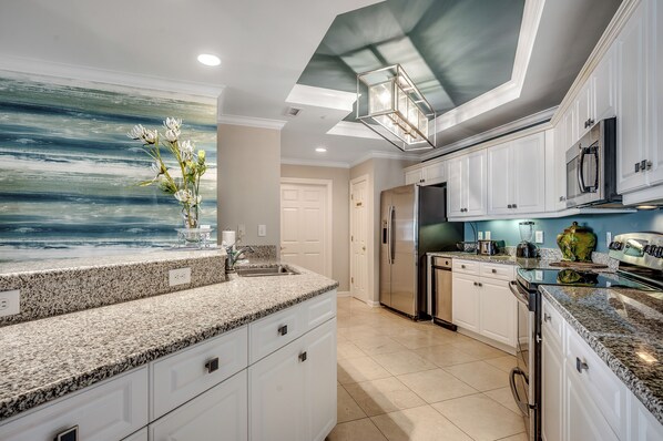 A modern kitchen with granite countertops, white cabinetry, and a large island.