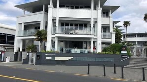 A modern hotel with a reception area, multiple floors, and a gated entrance. - Paihia Waterfront 1 Bedroom Apt & Pool (Paihia)