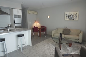 Una cocina moderna con una isla integrada, un comedor con mesa y sillas, y una sala de estar con sofá y mesa de centro.