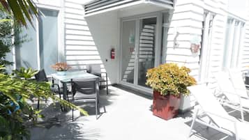 Eine Terrasse mit Tisch und Stühlen, einem Blumentopf und einem Feuerlöscher.