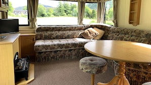 A cozy RV interior with a sofa, a small table, a television, and a piano.