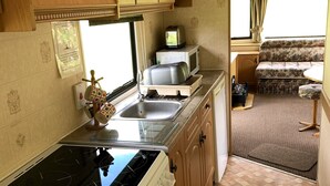 A compact RV kitchen with a stove, oven, microwave, and sink.