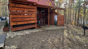 A rustic cabin with a wooden exterior, a porch, and a small attached shed.