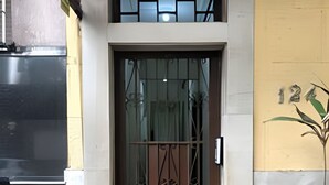 Une porte surmontée d’un portail en métal, une petite marche menant à cette porte, et un mur sur lequel est peint le chiffre « 12 ».