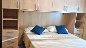 Une chambre à coucher comprenant un lit, deux oreillers, une table de chevet et des armoires encastrées en bois.