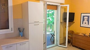 Une cuisine équipée d’un réfrigérateur, d’un four à micro-ondes et d’un téléviseur posé sur un meuble.
