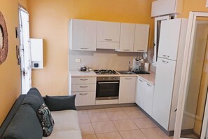 Una cocina compacta con muebles blancos, estufa y lavamanos.