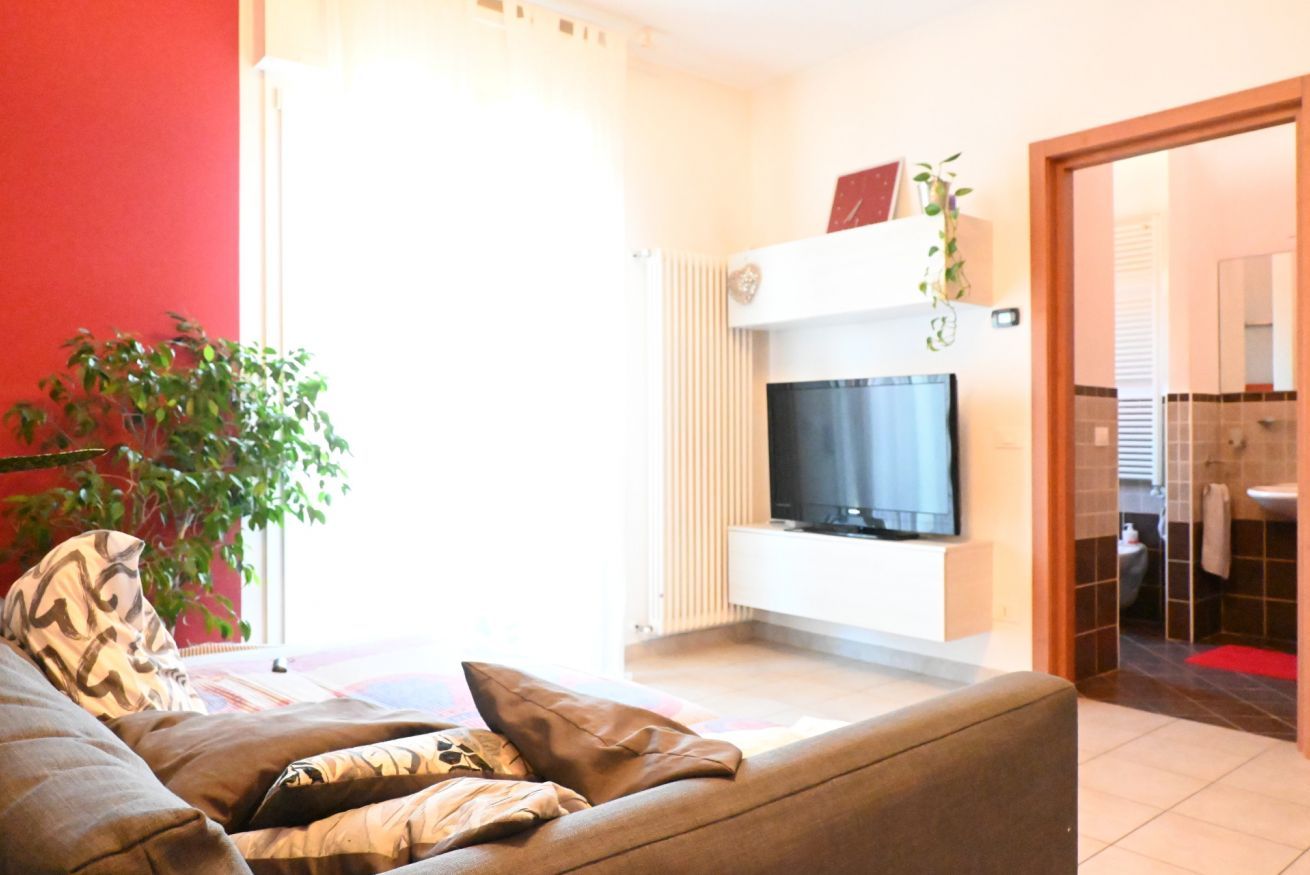 En stue med sofa, fjernsyn, radiator og et planter.