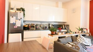 A compact kitchen with white cabinets, a refrigerator, a dining table, and a sofa. - CN004 - Cesenatico, new penthouse with terrace and Jacuzzi (Cesenatico)