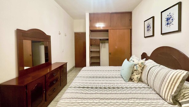 A bedroom with a bed, dresser, mirror, wardrobe, and two framed pictures on the wall. - Villa by Centro Medico Occidente 3 br (Guadalajara)