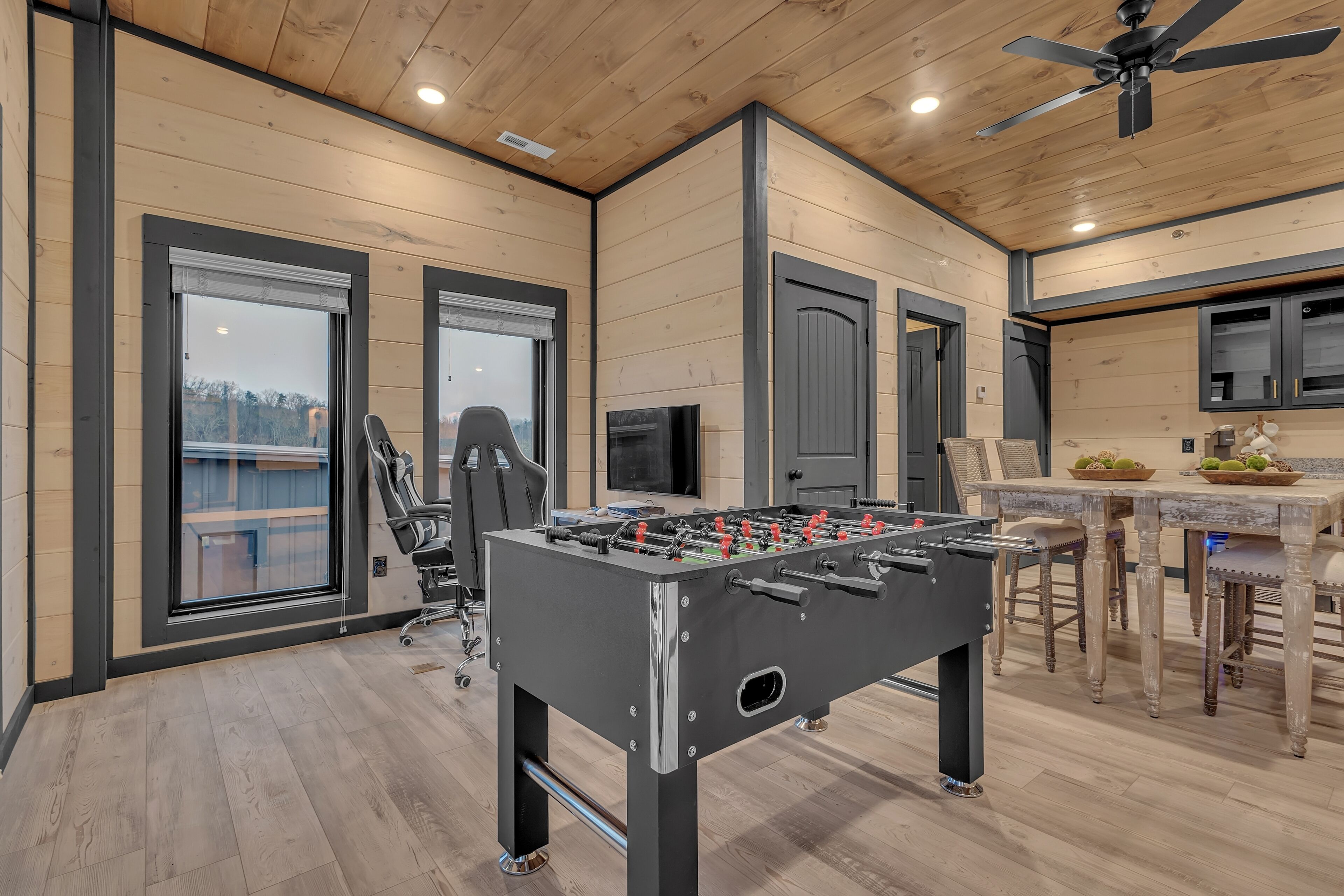 Une chambre moderne équipée d’un baby-foot, d’un fauteuil de jeu et d’un coin bar avec des tabourets.