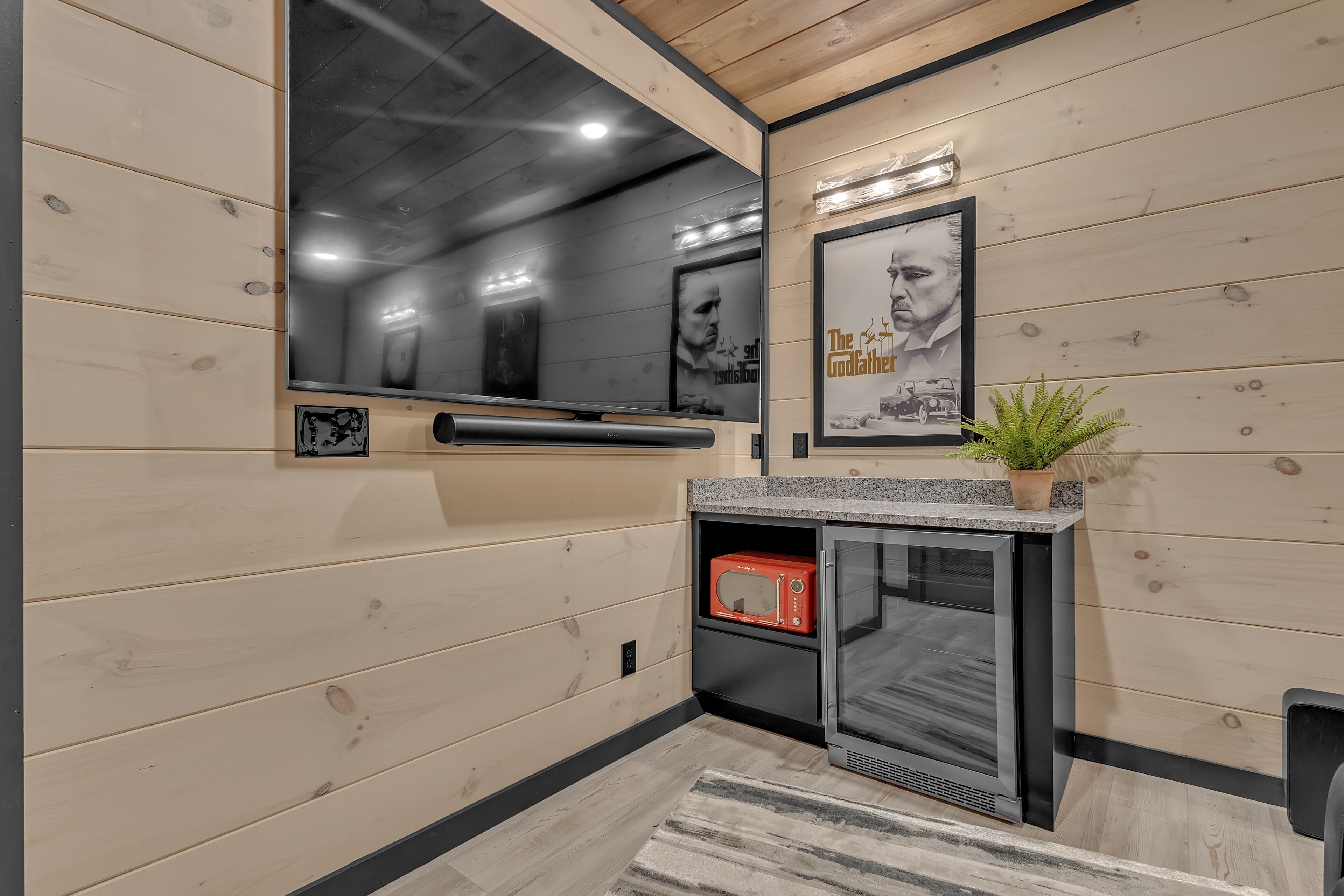 A modern kitchen with wooden panel walls, a built-in microwave, and a framed poster on the wall.