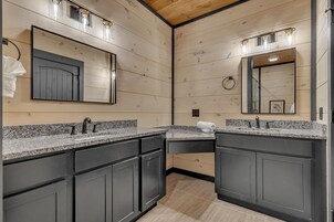 Un bagno moderno con due lavabi, mobili scuri e pareti in legno.
