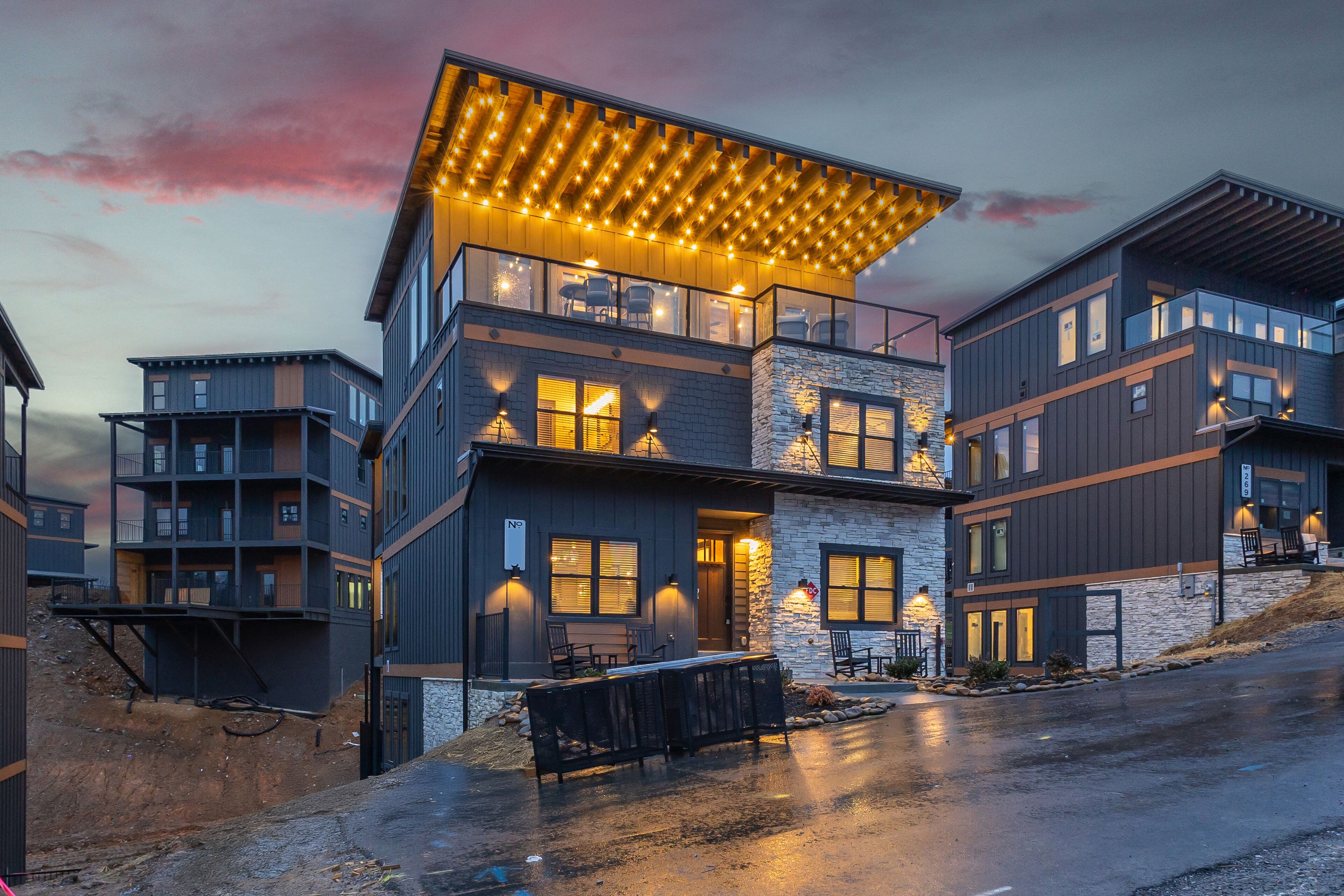 A multi-story building with a flat roof, large windows, and a covered outdoor seating area.