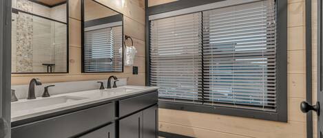 A modern bathroom with two sinks, a large mirror, and wooden walls.
