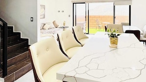 Un comedor moderno con una mesa de mármol y sillas de cuero, una escalera y vistas al exterior.