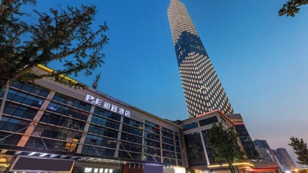 A modern building with a prominent glass facade and a tall, illuminated tower. - Peace & Ease Hotel (Suzhou Jinji Lake Expo Center) (Suzhou)