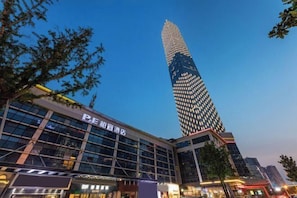 Een modern gebouw met een opvallende glazen gevel en een hoge, verlichte toren.