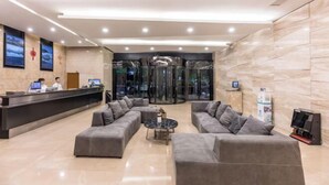 A modern hotel lobby with a reception desk, seating area, and a glass elevator. - Peace & Ease Hotel (Suzhou Jinji Lake Expo Center) (Suzhou)
