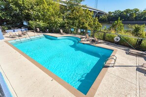 Une piscine rectangulaire à l’eau d’un bleu limpide, entourée de chaises longues et protégée par une barrière de sécurité.