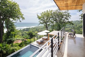 A rooftop infinity pool with lounge chairs and umbrellas, overlooking a coastal landscape. - Villa Nof Yam Luxury Villa Santa Teresa (Cobano)