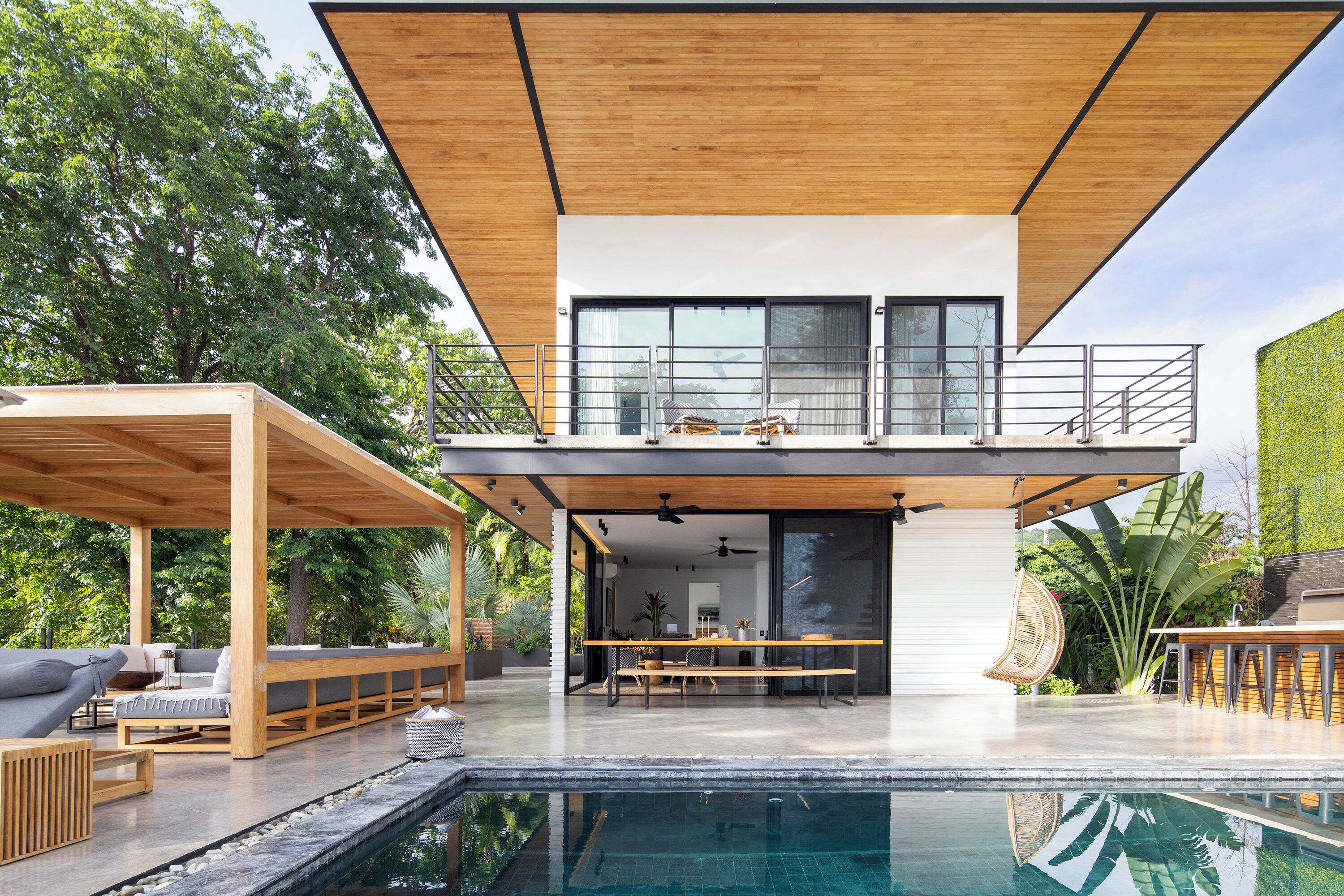 Una casa moderna con piscina, terrazza in legno e zona pranzo.