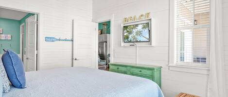 A bedroom with a bed, a green dresser, a wooden bench, and a window with blinds.