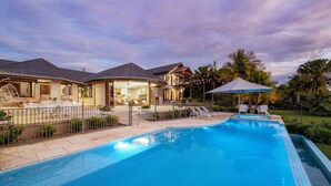 A modern house with a swimming pool, outdoor seating, and a well-maintained garden.