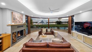 A modern living room with a fireplace, leather sofa, and a large TV screen.