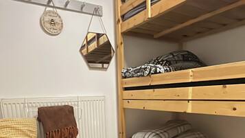 A room with a bunk bed, a patterned rug, a radiator, and a wall-mounted decoration.