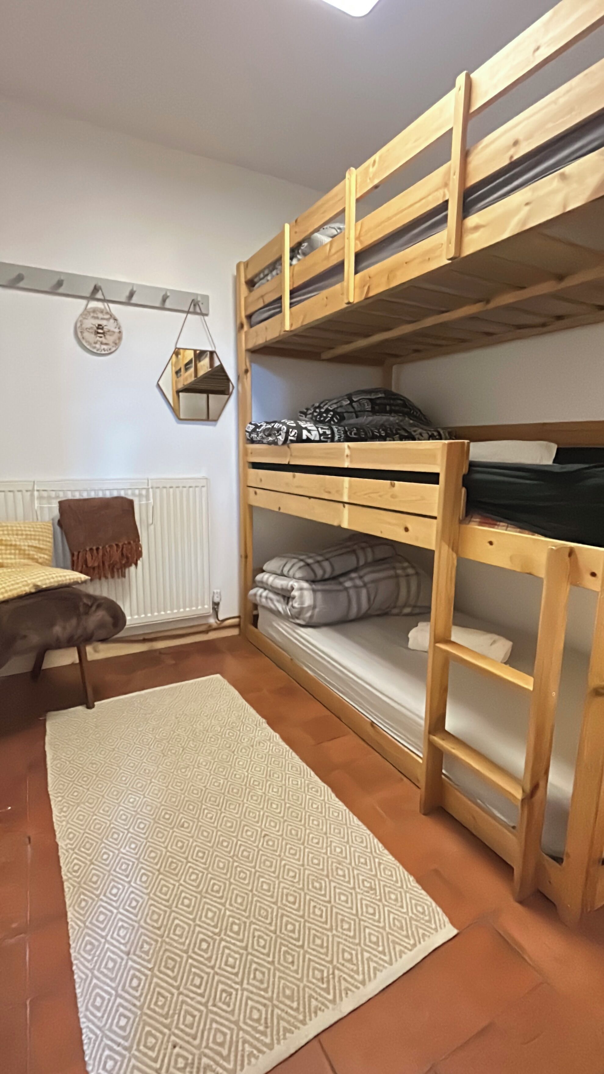 Ein Schlafzimmer mit Etagenbett, Heizkörper, einem gemusterten Teppich und einer hängenden Dekoration.