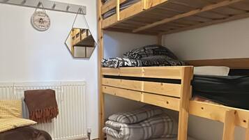 Ein Schlafzimmer mit Etagenbett, Heizkörper, einem gemusterten Teppich und einer hängenden Dekoration.