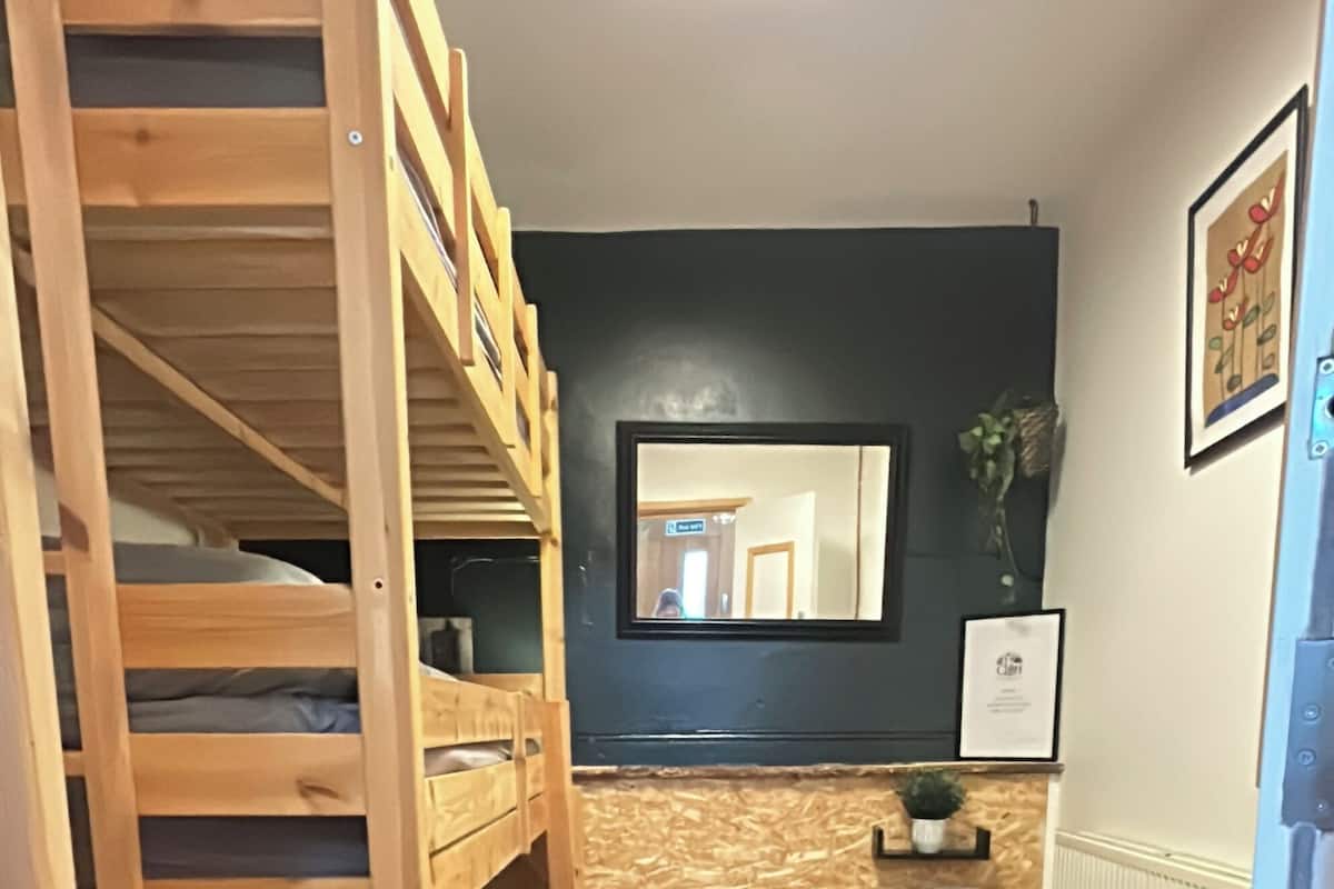 A room with a bunk bed, a radiator, a mirror, and a chair.