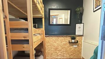 Una habitación con una cama litera, un radiador, un espejo y una silla.