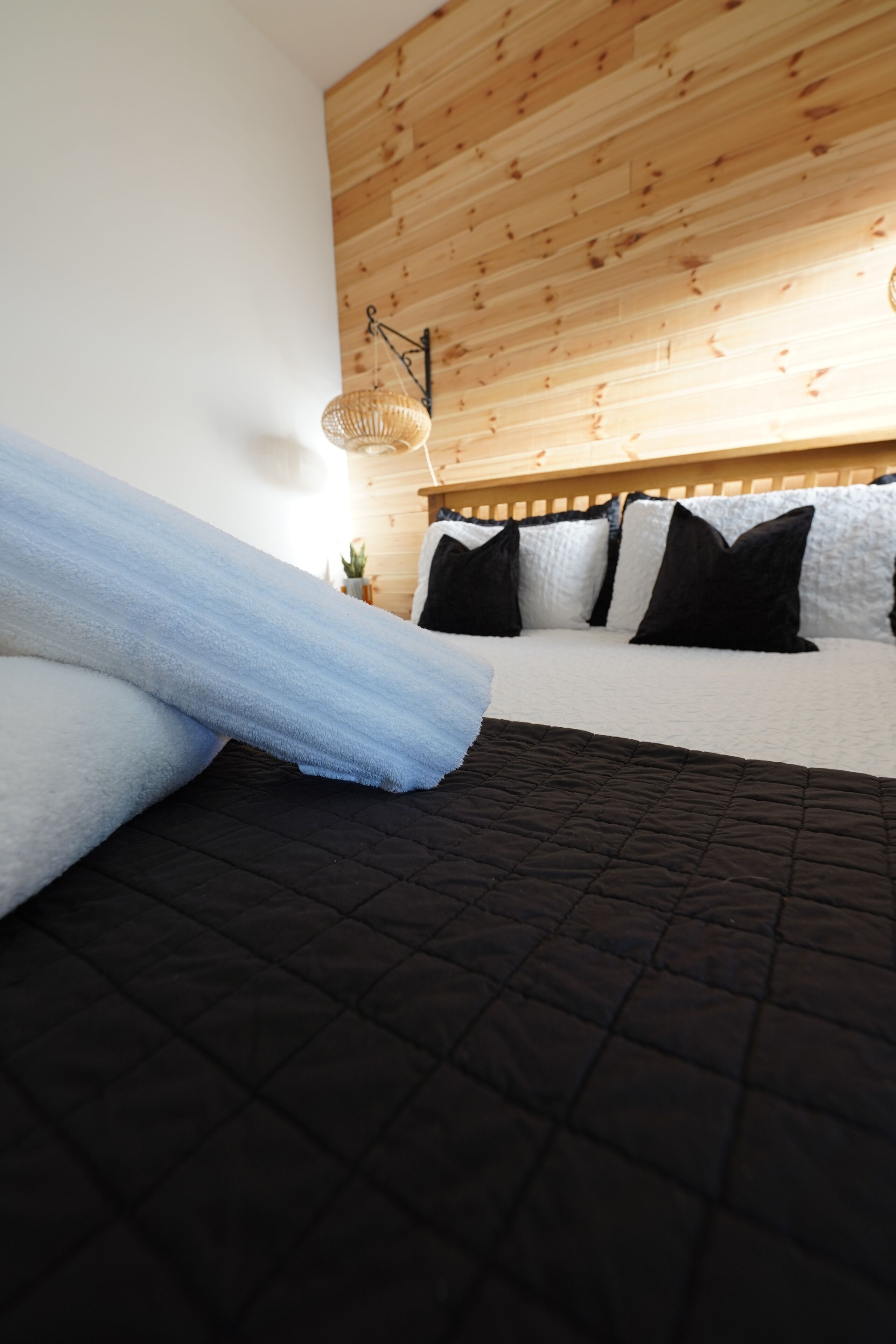 A bed with a black quilt, white and blue pillows, and a wooden headboard.