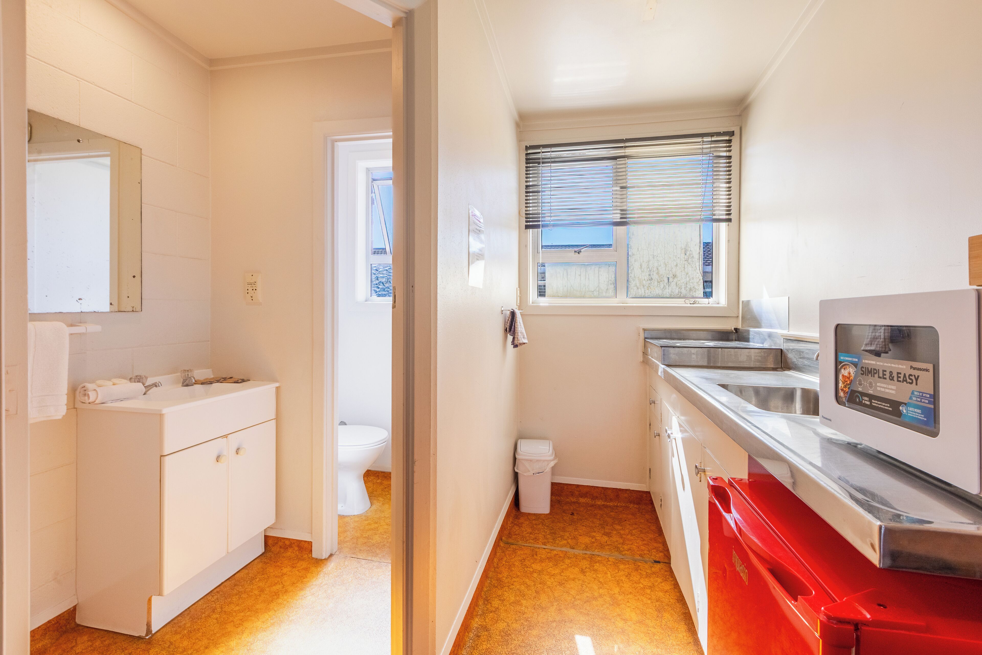 A compact kitchen with a sink, countertop, and a window with blinds.