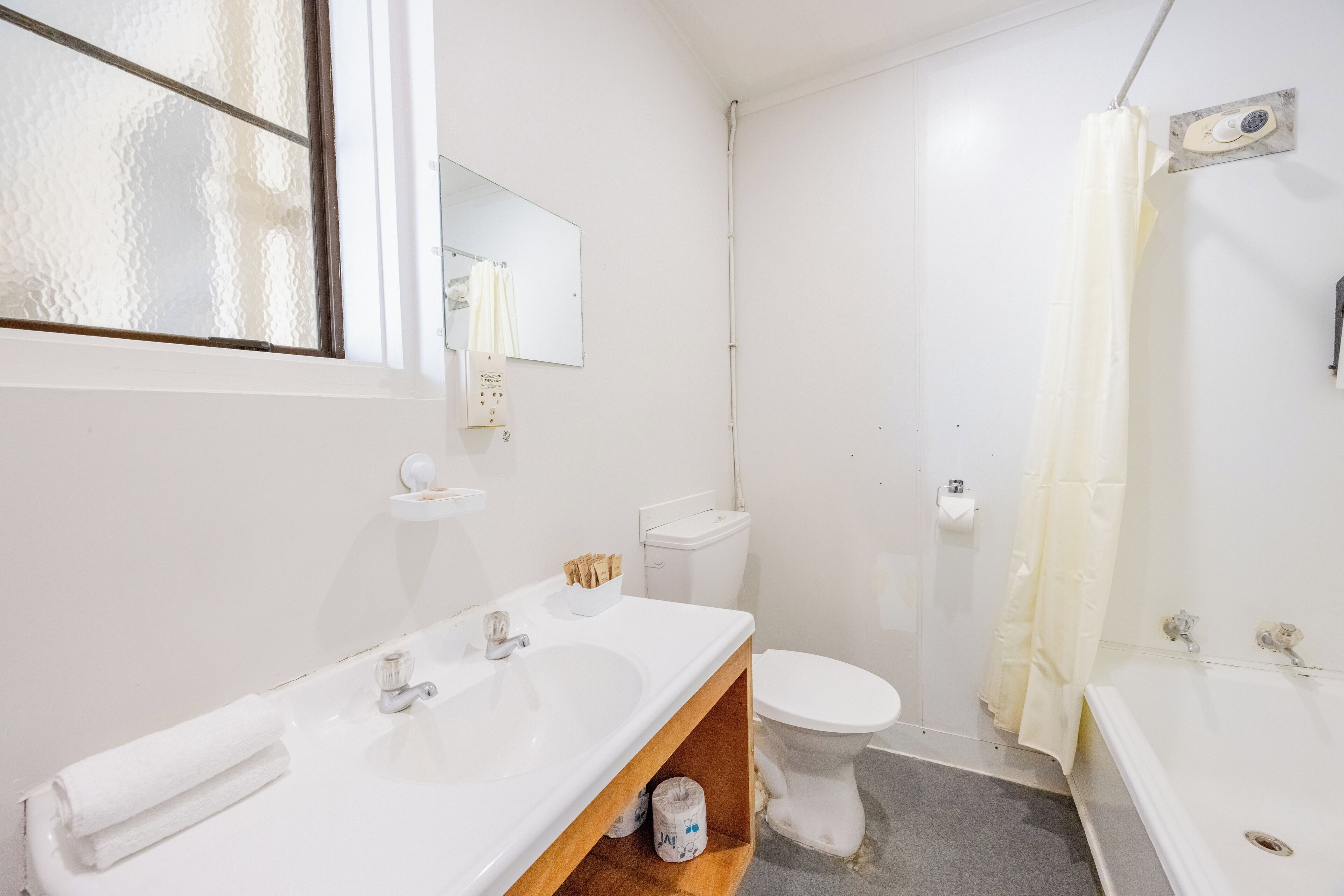 A bathroom with a white sink, toilet, and bathtub. There is a mirror above the sink and a shower curtain.