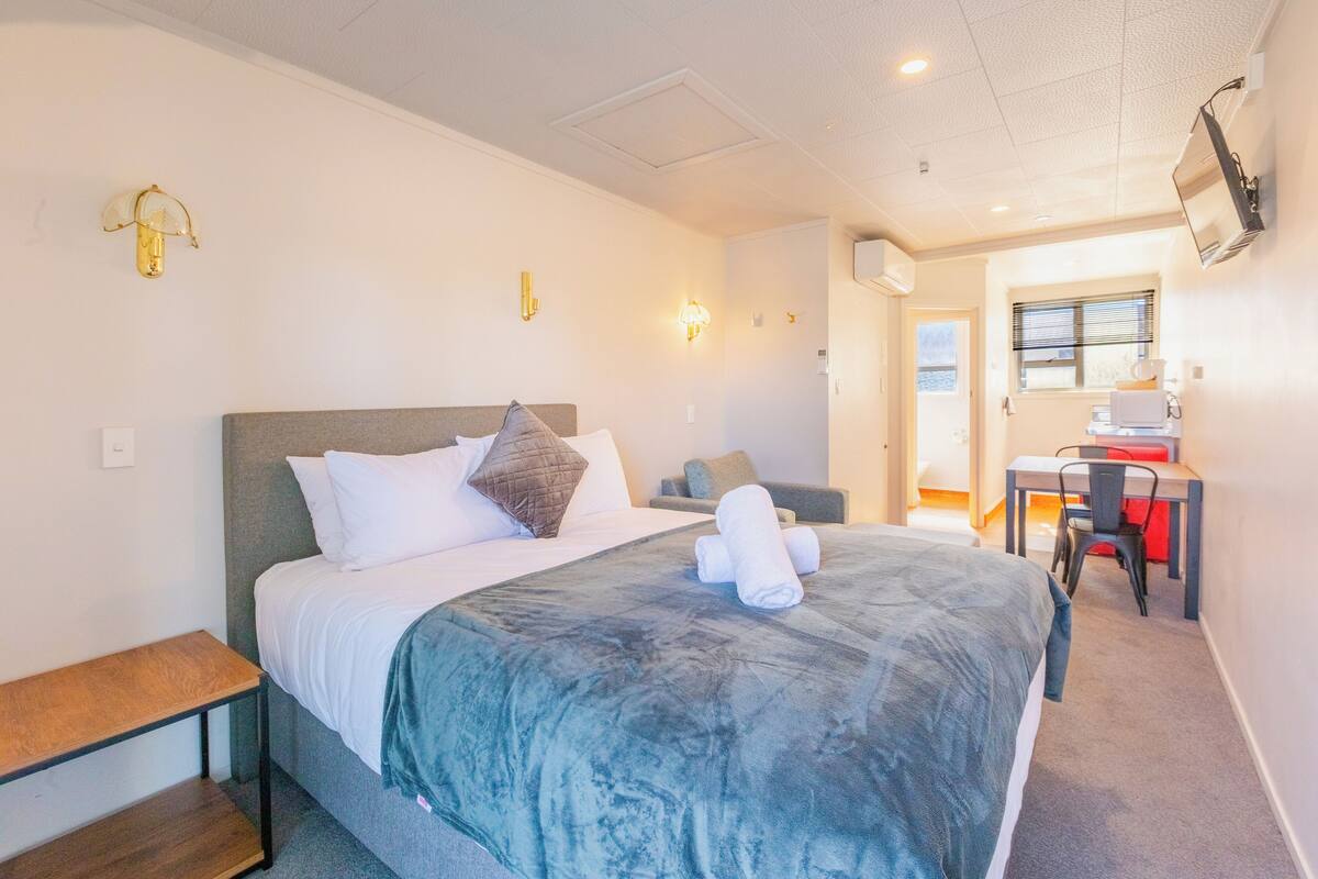 A hotel room with a bed, a desk, and a chair.