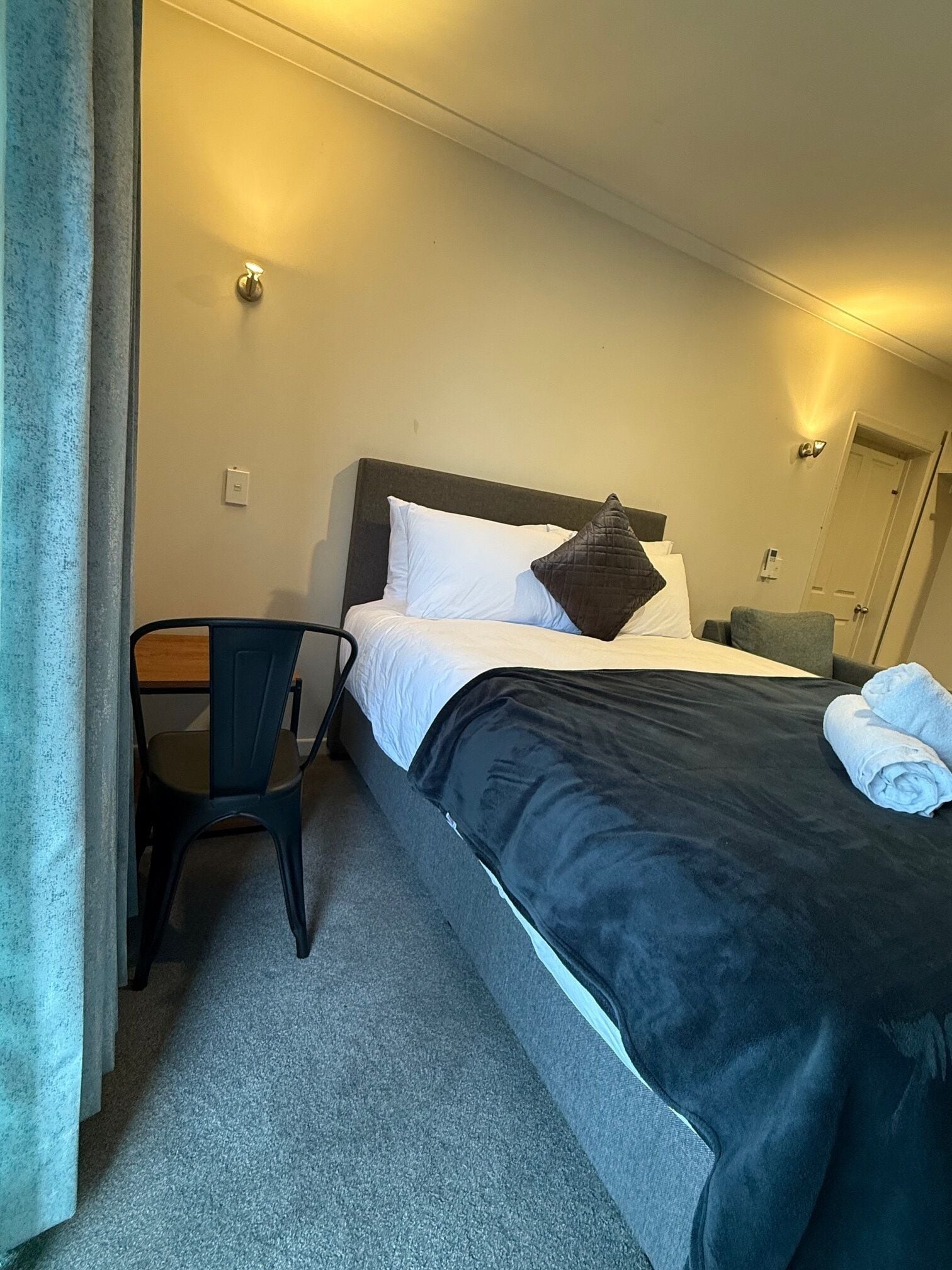 Habitació d'hotel amb un llit, una cadira i un escriptori.