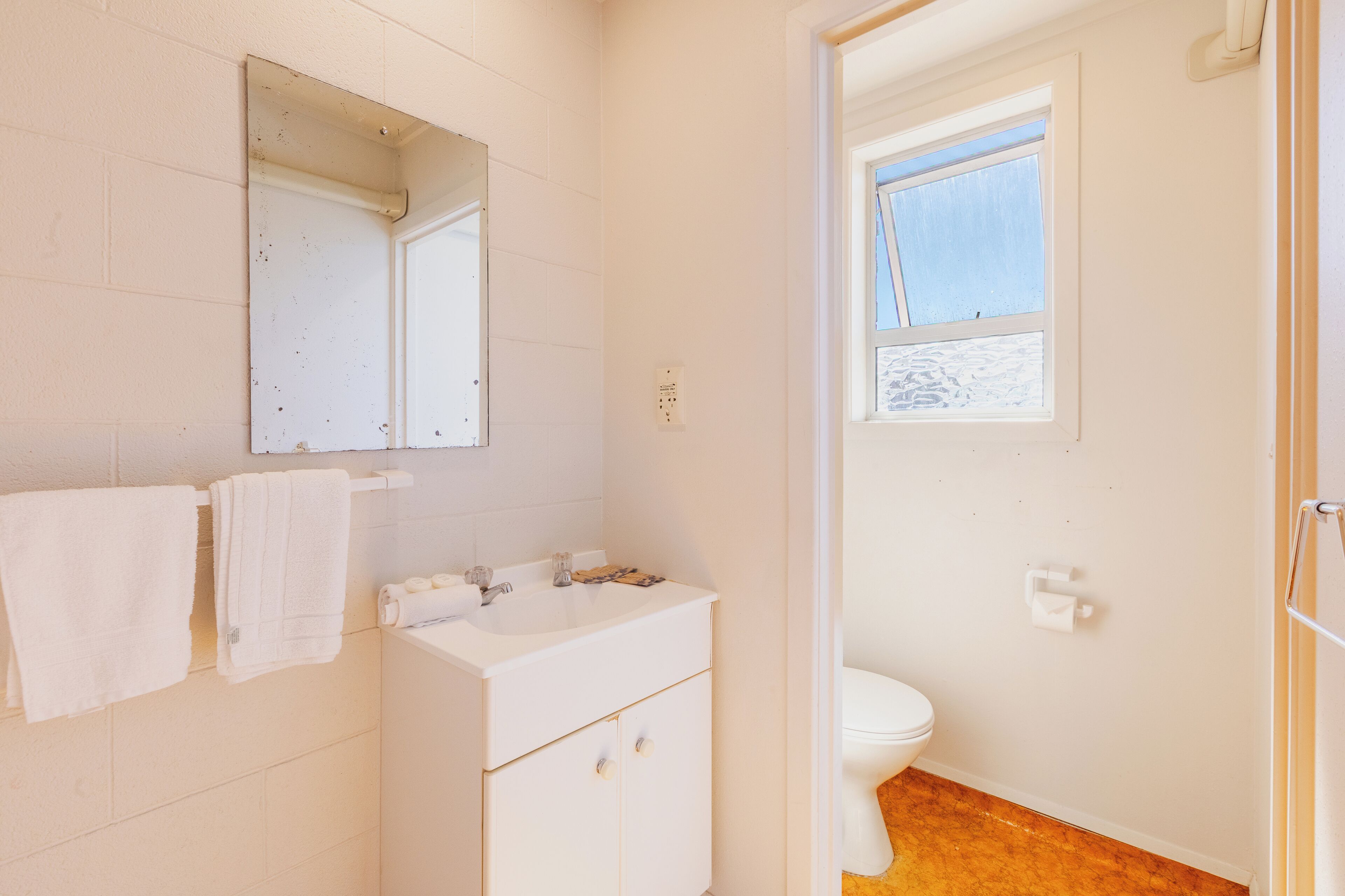 A bathroom with a white sink, mirror, and toilet.