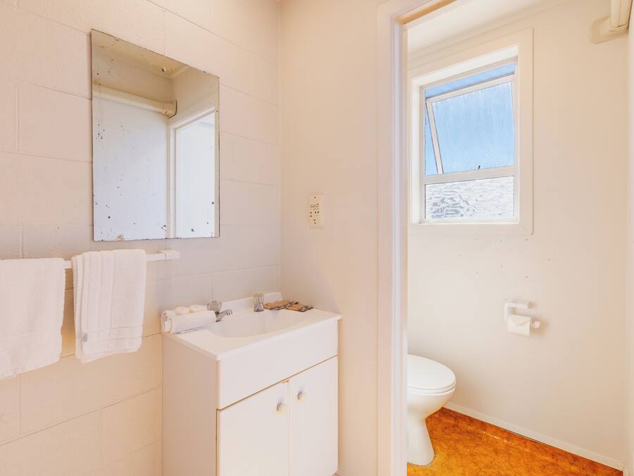Un baño con lavamanos blanco, espejo y retrete.