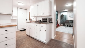 A modern kitchen with white cabinets, a microwave, and a sink. - The Cloud off 16th  (Calgary)