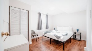 A bedroom with a bed, a chair, a bedside table, and a wardrobe. - The Cloud off 16th  (Calgary)