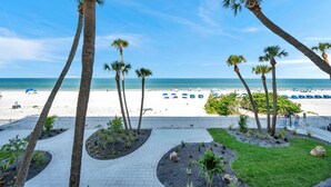 A beach view with palm trees, a pathway, and beach umbrellas. - Beachfront 3 bedroom with Amazing Views! (Indian Shores)