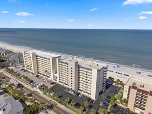 A beachfront hotel with multiple floors, parking, and a view of the ocean.