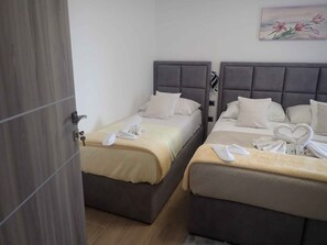 A hotel room with two beds, each with a grey headboard, white bedding, and towels. - Holiday apartment with sea view (Barić Draga)