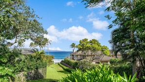 A coastal property with a view of the ocean, surrounded by lush greenery and a stone wall. - Kapalua Ridge Villas 1023 (Lahaina)