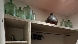 A storage closet with shelves, a red carpeted floor, and various items including a metal pot and green glass bottles. - Cazules #2 (Puerto Vallarta)