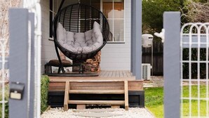 A house with a porch, a hanging chair, and a wooden deck.