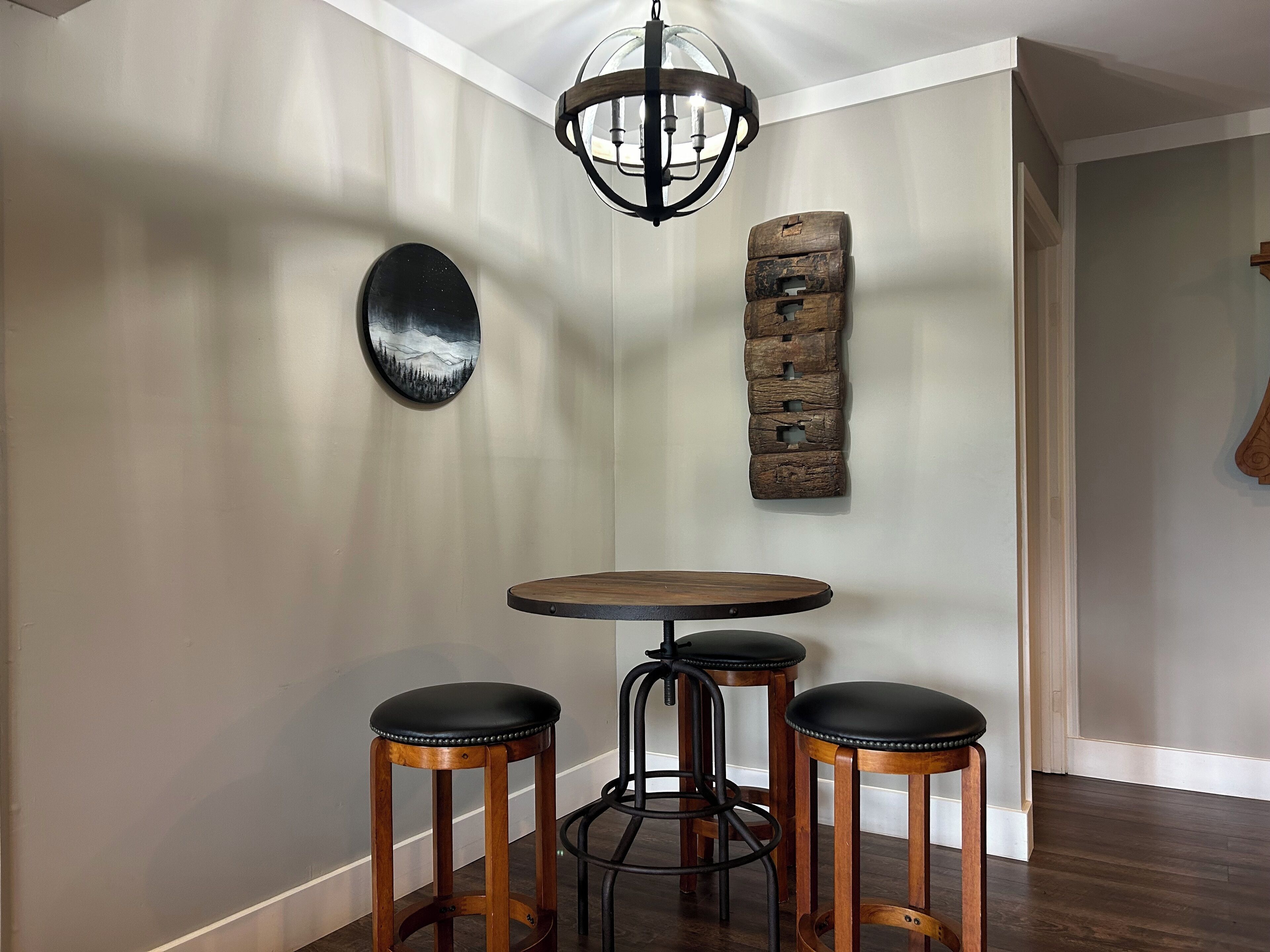 A dining area with a round wooden table and three stools.